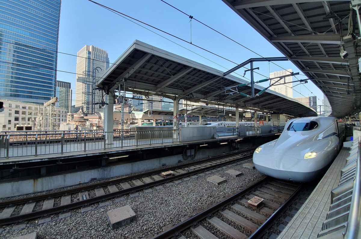 An N700 series Shinkansen waiting at Tokyo Station below the Marunouchi skyline